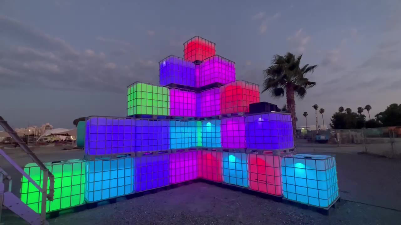 Pyramid of water tanks lit in blocks of colour at dusk